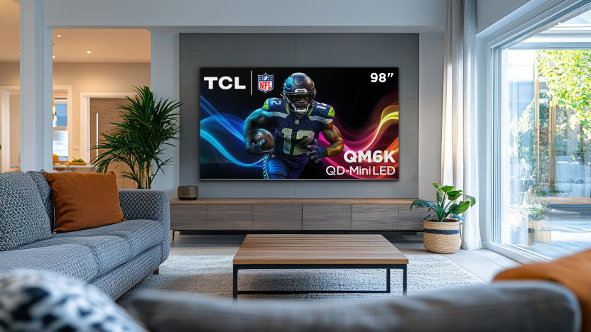 A TCL QM6K flatscreen QD-Mini LED TV on a living room wall.